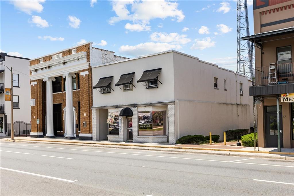 A street-level view of a commercial building with a salon storefront and adjacent brick structure — 61 N CENTRAL AVENUE, UMATILLA, FL
