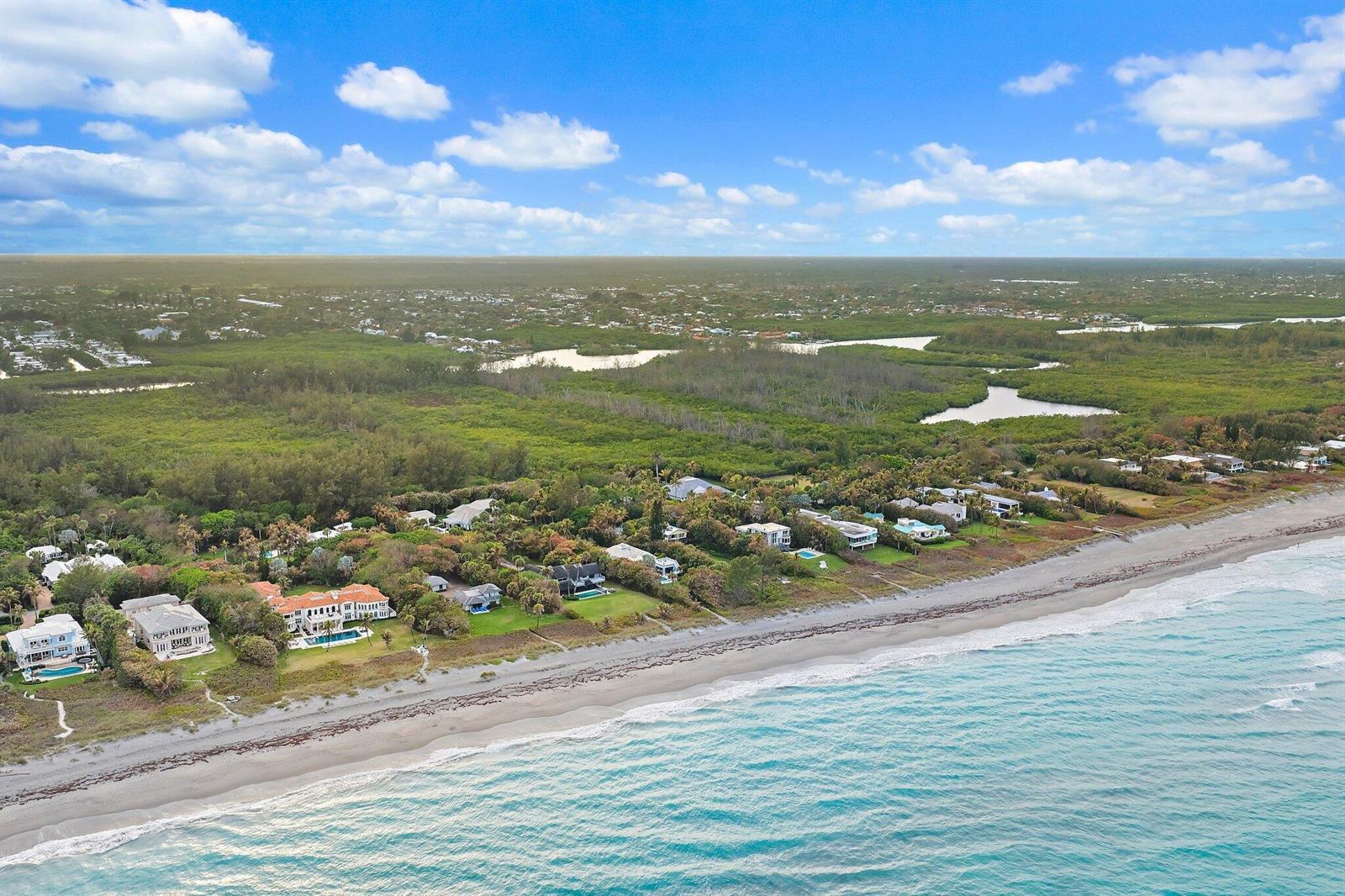 An aerial view shows luxury beachfront homes nestled along a coastline with dense green vegetation — 31 N Beach Road, Jupiter Island FL 33455, JUPITER ISLAND, FL