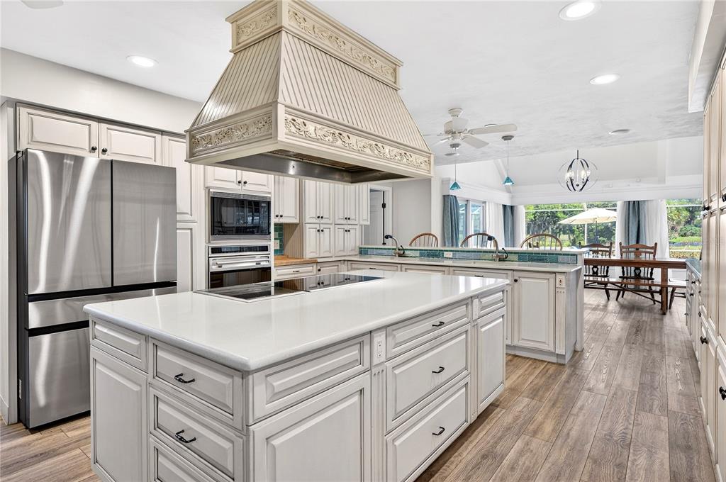 A kitchen with a large central island, stainless steel appliances, and a decorative range hood — 770 PELICAN BAY DRIVE, DAYTONA BEACH, FL