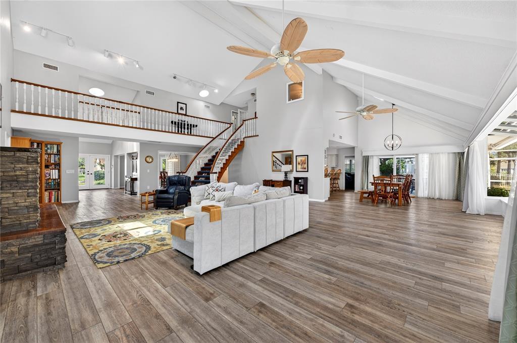 A spacious living room features vaulted ceilings, wood-look flooring, a stone fireplace, and a loft — 770 PELICAN BAY DRIVE, DAYTONA BEACH, FL