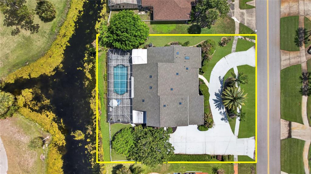 An aerial view shows a house with a screened-in pool, driveway, and surrounding landscaping — 770 PELICAN BAY DRIVE, DAYTONA BEACH, FL