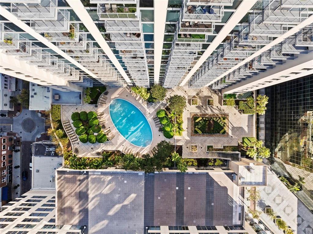 An aerial view of a high-rise apartment building courtyard featuring a pool and landscaped garden — 155 S COURT AVENUE UNIT 1705, ORLANDO, FL