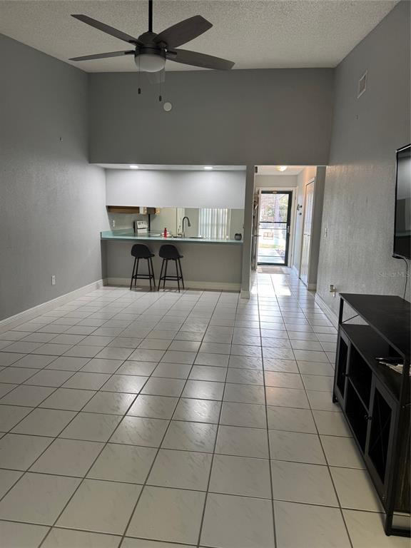 A living area with white tile floors, a ceiling fan, and a kitchen breakfast bar — 3321 ROYAL STREET, WINTER PARK, FL