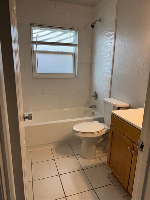 A bathroom featuring a white bathtub with tiled walls, a toilet, and a wooden vanity — 3321 ROYAL STREET, WINTER PARK, FL
