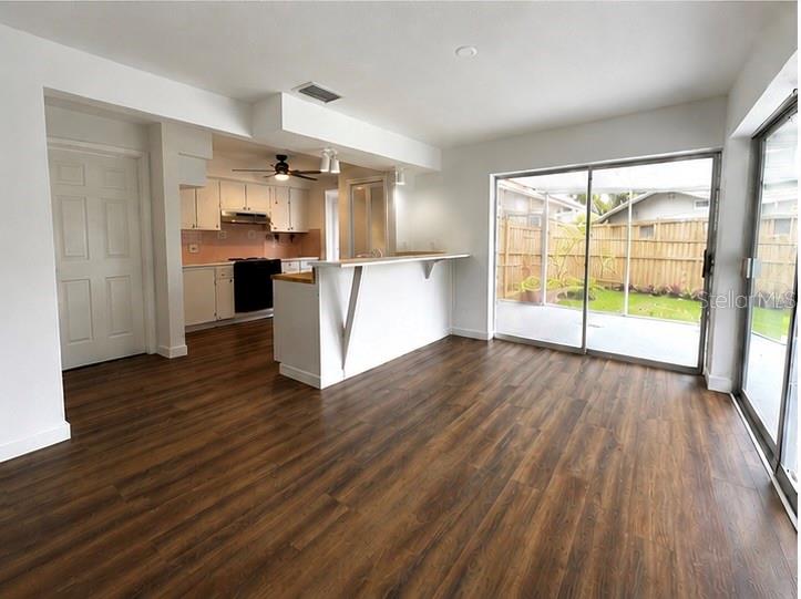 An open-concept kitchen and living area with wood-look flooring and sliding glass doors to a patio — 12620 82ND TERRACE, SEMINOLE, FL
