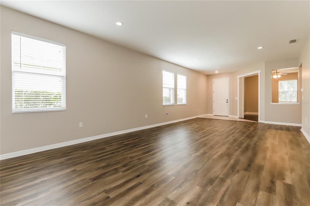 An empty living room features light-colored walls, recessed lighting, and dark wood-look plank flooring — 1035 CLEARPOINTE WAY, LAKELAND, FL