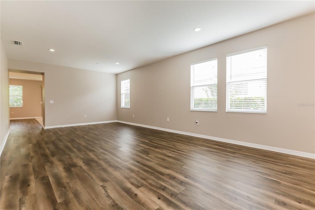 An empty room features light-colored walls, recessed lighting, and wood-look flooring with multiple windows — 1035 CLEARPOINTE WAY, LAKELAND, FL