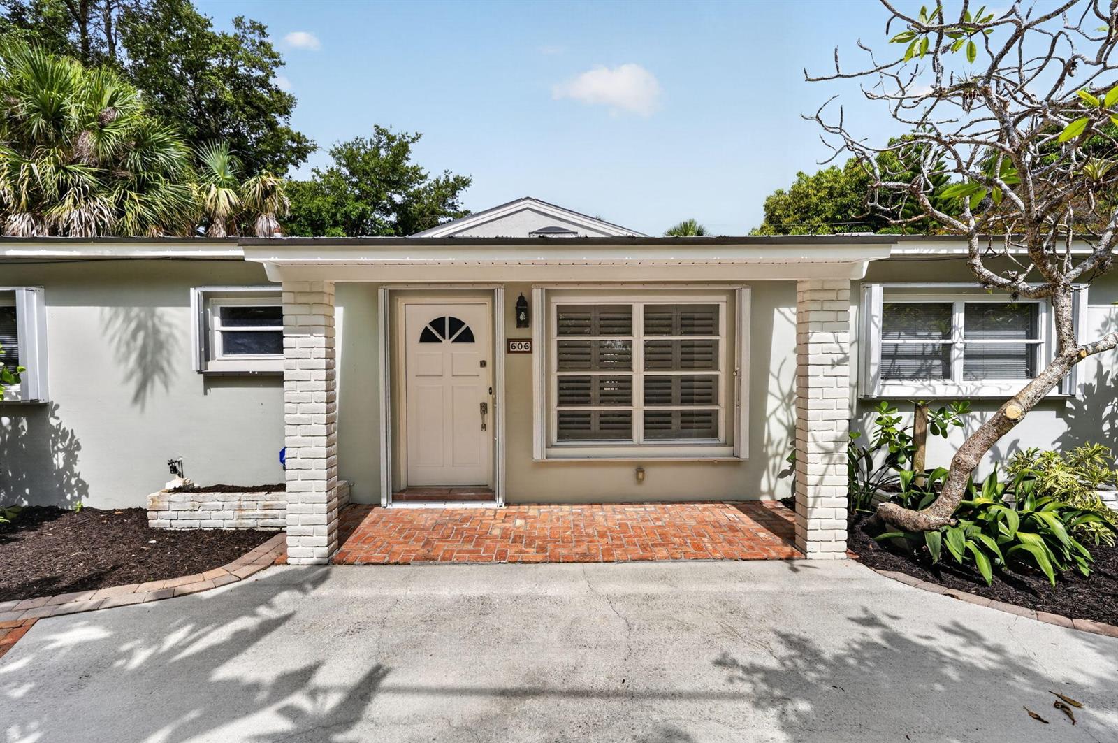 The exterior of a single-story house features a brick porch, white columns, and a driveway — 606 Paulina Road, Jupiter FL 33477, JUPITER, FL