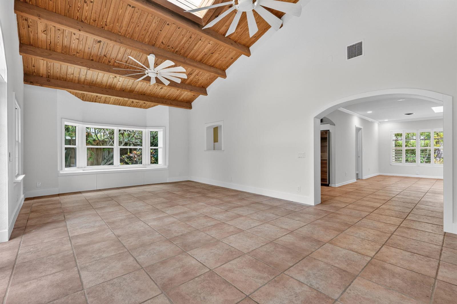 A spacious living room features a vaulted wood-paneled ceiling, tile flooring, and a bay window — 606 Paulina Road, Jupiter FL 33477, JUPITER, FL