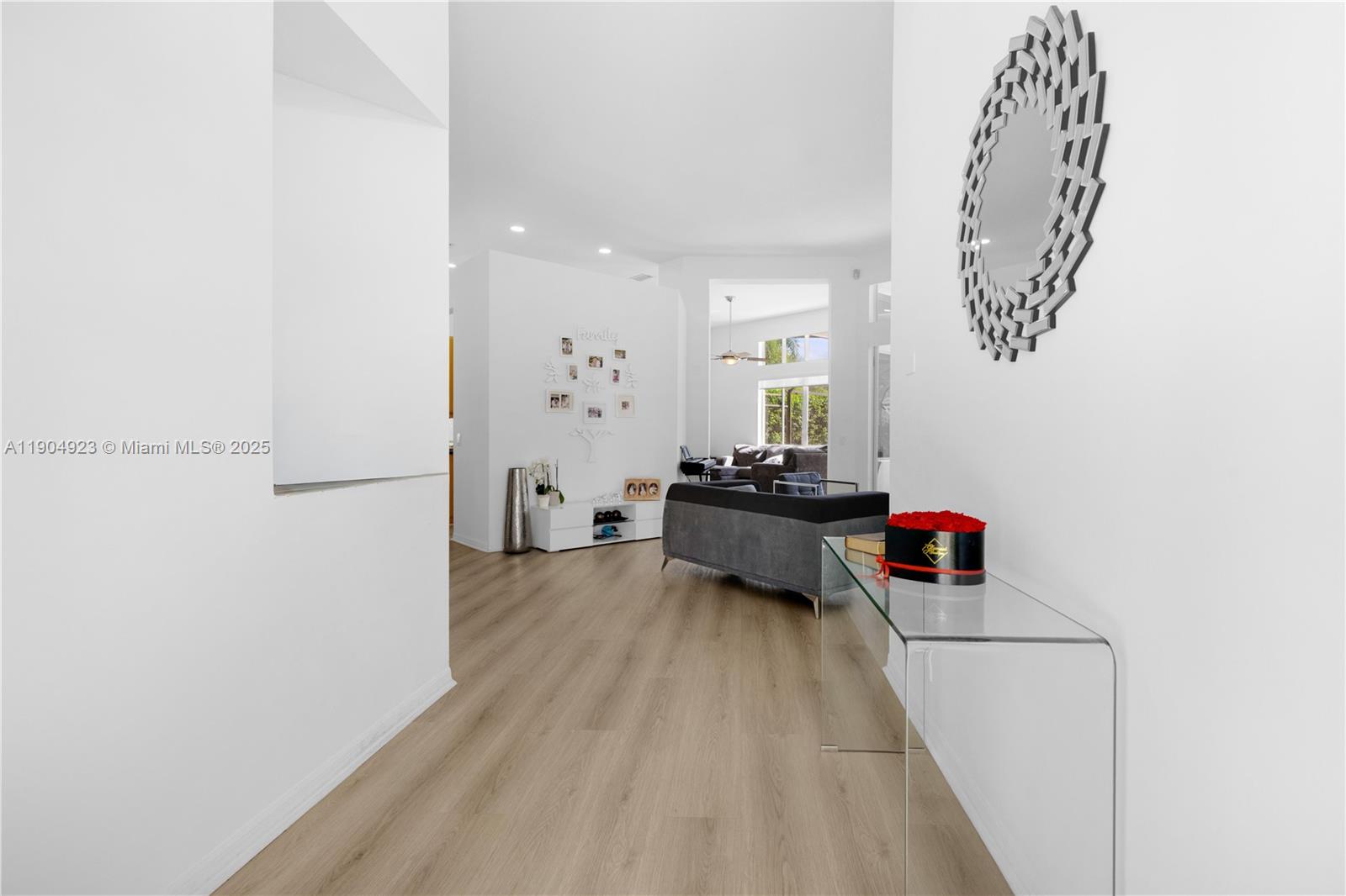 A bright hallway with light wood flooring leads into a living room with white walls — 1102 Camellia Cir, Weston FL 33326, WESTON, FL