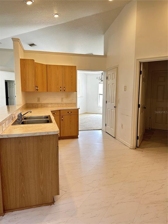 A kitchen features light wood cabinets, laminate countertops, and white tile flooring — 13540 SW 86TH AVENUE, OCALA, FL
