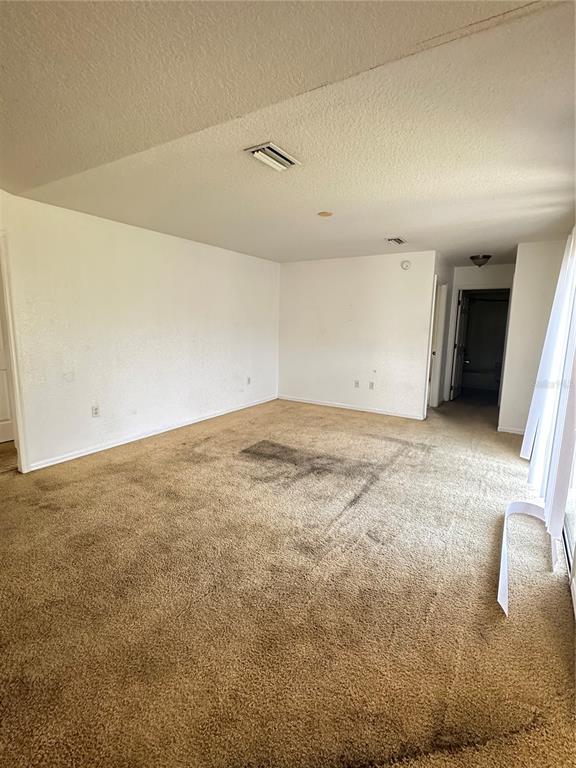 An empty room with beige carpet, white walls, and a sliding glass door — 13540 SW 86TH AVENUE, OCALA, FL