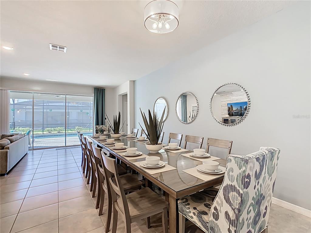 A dining room features a glass-topped table, upholstered chairs, and three circular wall mirrors — 4125 LANA AVENUE, DAVENPORT, FL