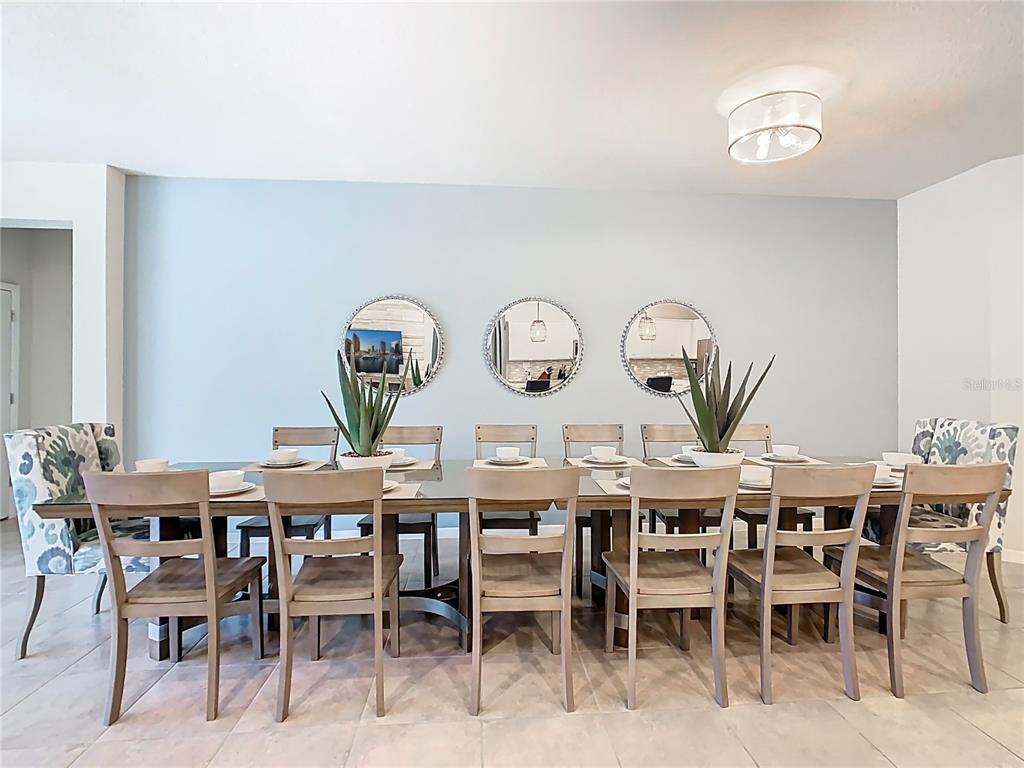 A dining room features a long table with ten chairs and three circular wall mirrors — 4125 LANA AVENUE, DAVENPORT, FL