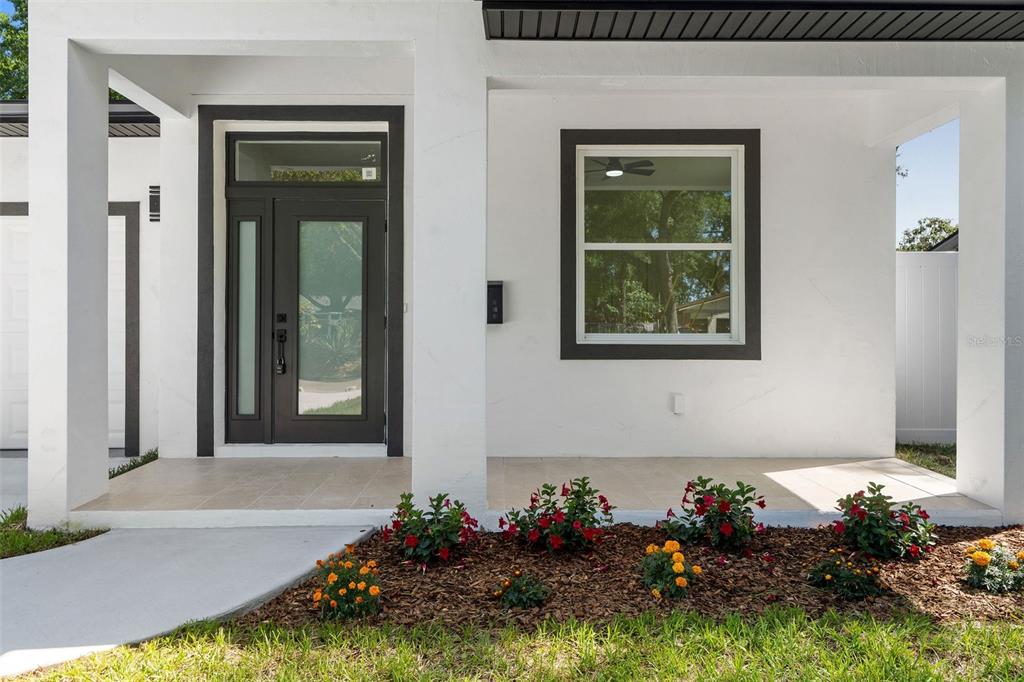 A modern white house exterior features a dark-framed front door and a single window — 2617 E PALIFOX STREET, TAMPA, FL