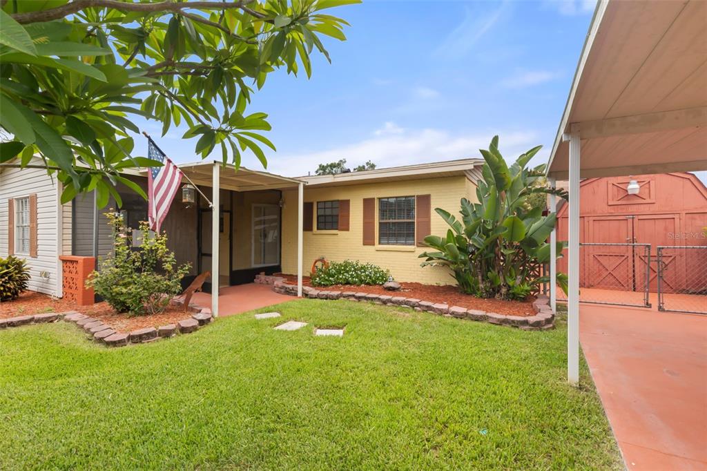 A yellow brick house with a screened porch, a front lawn, and a red shed — 4506 24TH AVENUE S, TAMPA, FL