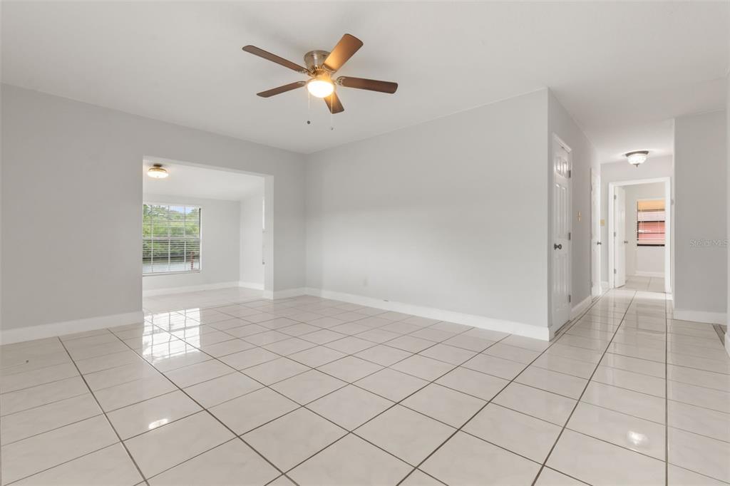 A bright, tiled living room features a ceiling fan and an adjacent sunroom — 4506 24TH AVENUE S, TAMPA, FL