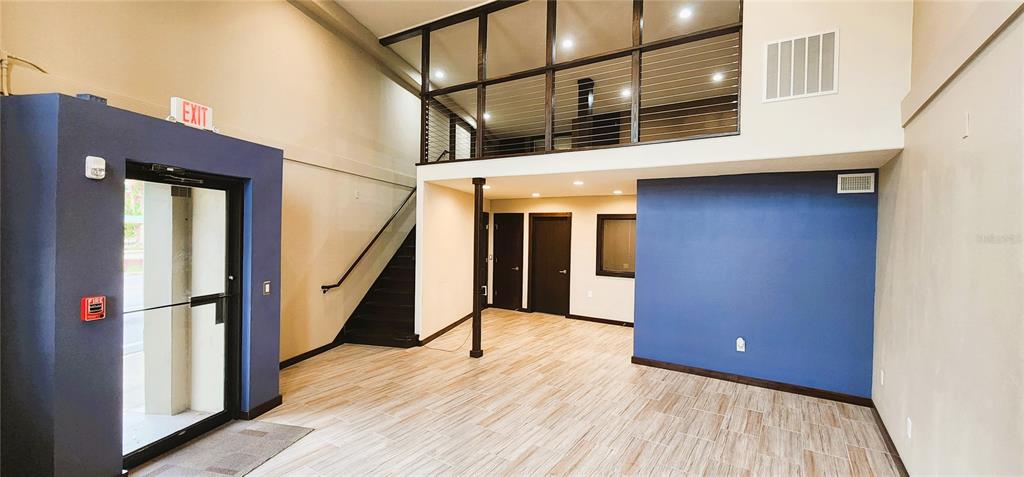 A modern interior features a blue accent wall, wood-look tile flooring, and a staircase leading upstairs — 251 E PARK AVENUE UNIT 102, LAKE WALES, FL