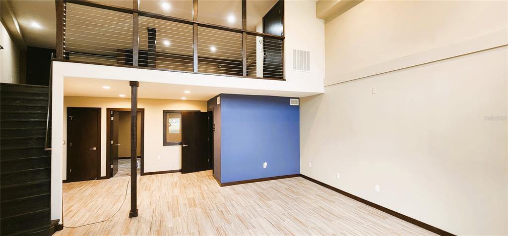 A room with wood-look tile flooring, a blue accent wall, and a lofted upper level — 251 E PARK AVENUE UNIT 102, LAKE WALES, FL