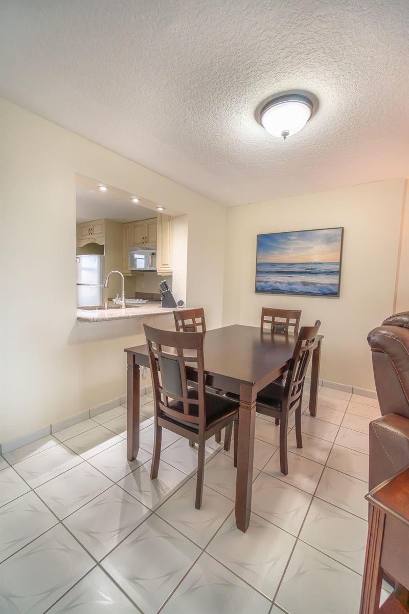 A dining area with a dark wood table and chairs adjacent to a kitchen pass-through — 131 SE 3rd Avenue # 608, Dania Beach FL 33004, DANIA BEACH, FL