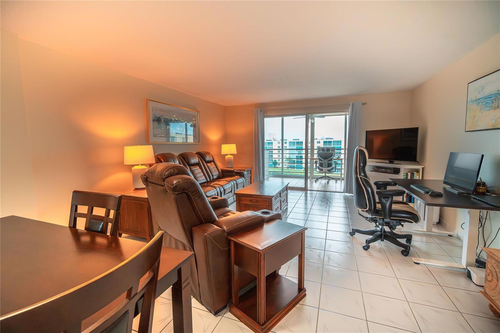 A living room with tile flooring, a leather sofa, a desk, and a balcony view — 131 SE 3rd Avenue # 608, Dania Beach FL 33004, DANIA BEACH, FL