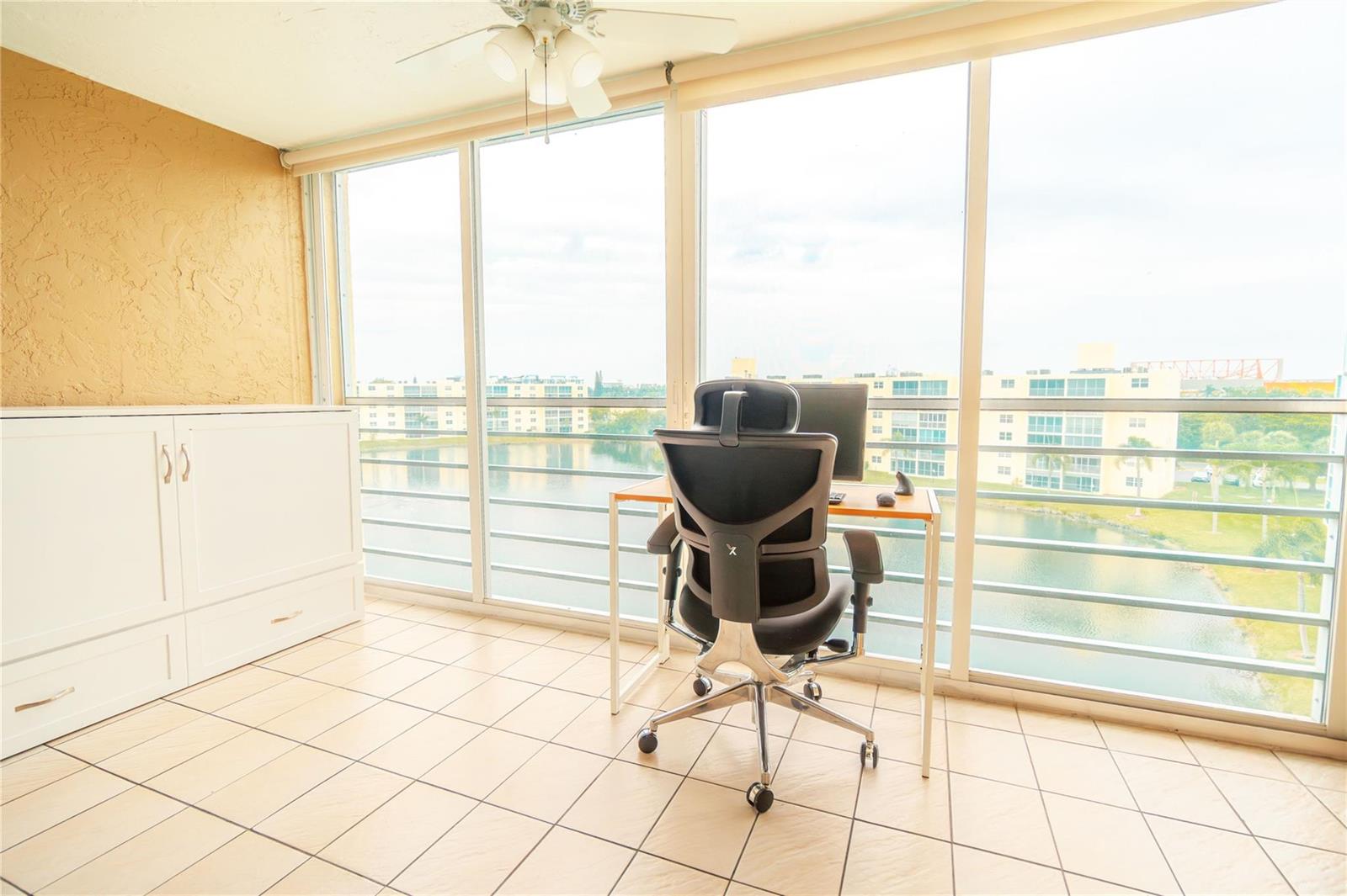 A home office with a desk and chair faces a large window overlooking a lake — 131 SE 3rd Avenue # 608, Dania Beach FL 33004, DANIA BEACH, FL