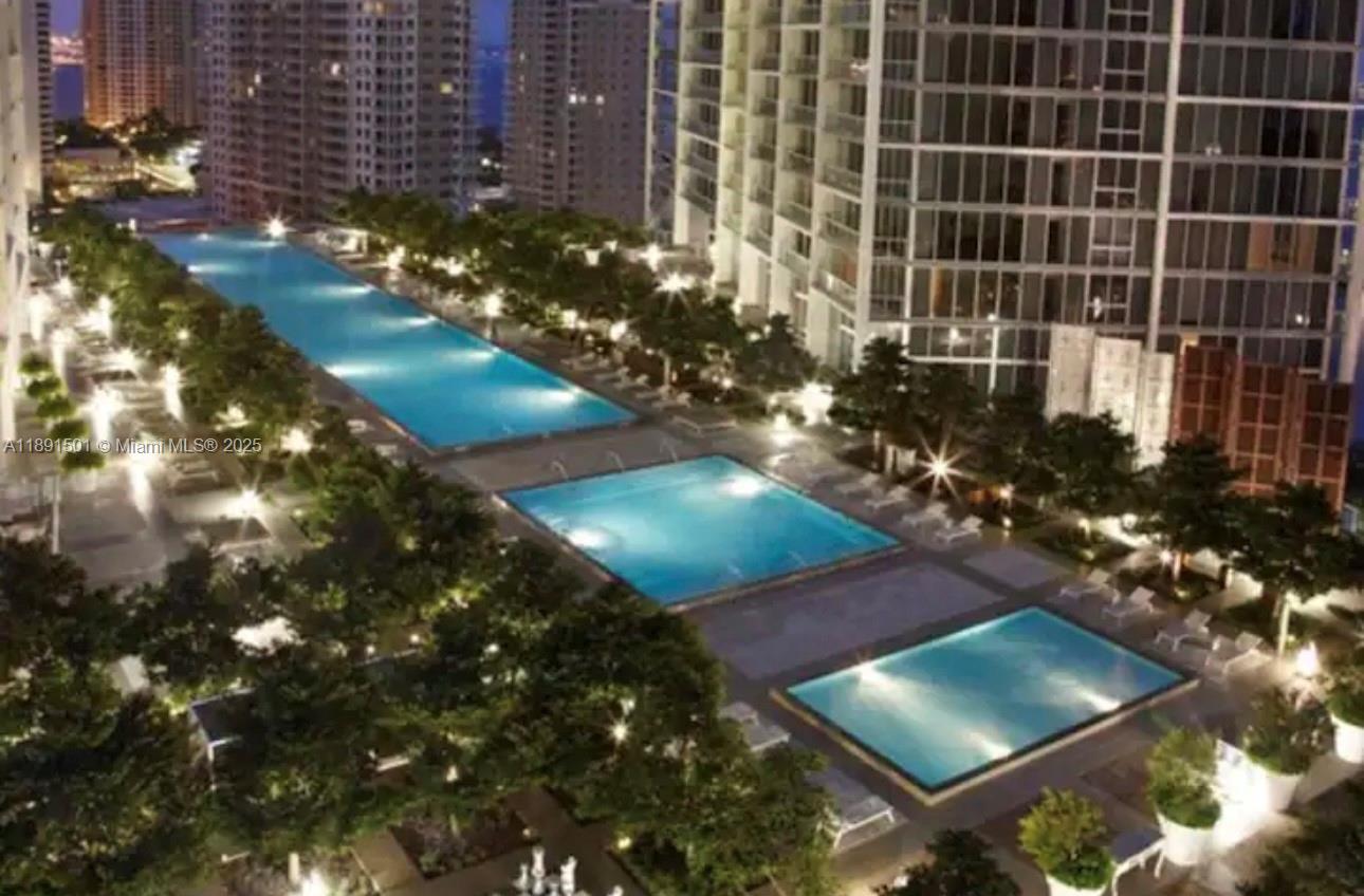 This exterior view shows a multi-level swimming pool area at night surrounded by high-rise buildings — 495 Brickell Ave # 3706, Miami FL 33131, MIAMI, FL