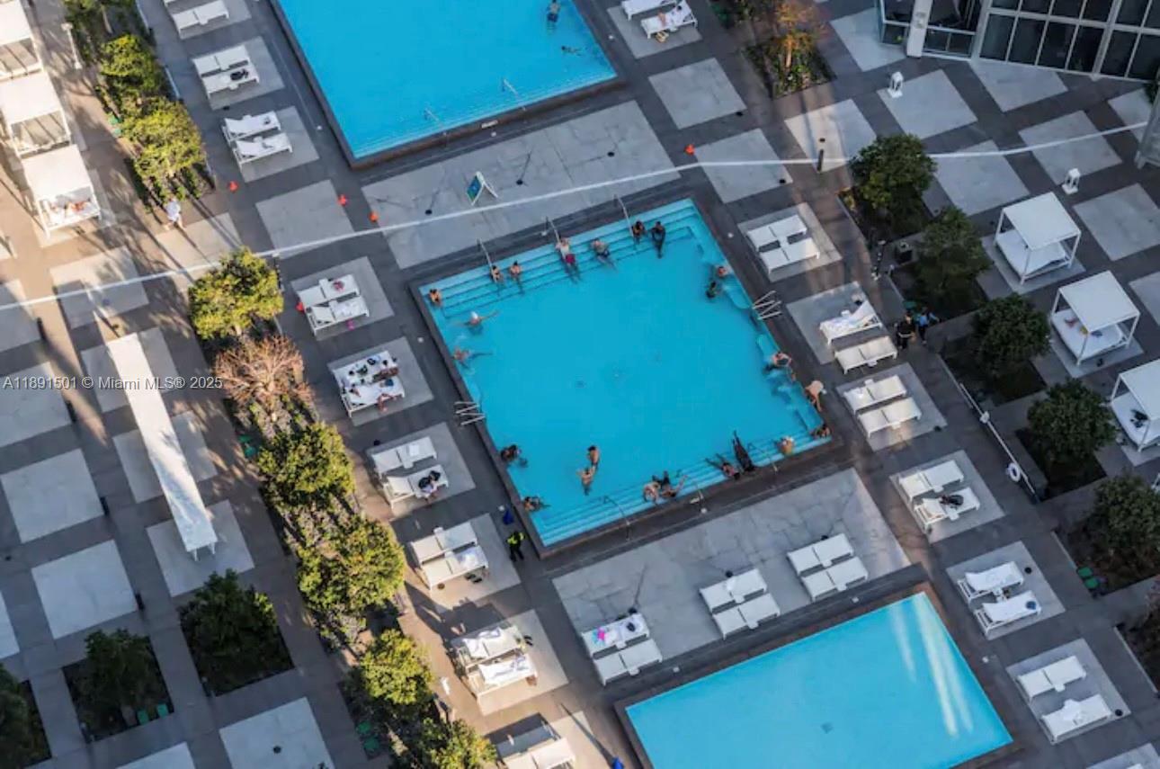 An aerial view shows a large square swimming pool surrounded by lounge chairs and landscaping — 495 Brickell Ave # 3706, Miami FL 33131, MIAMI, FL