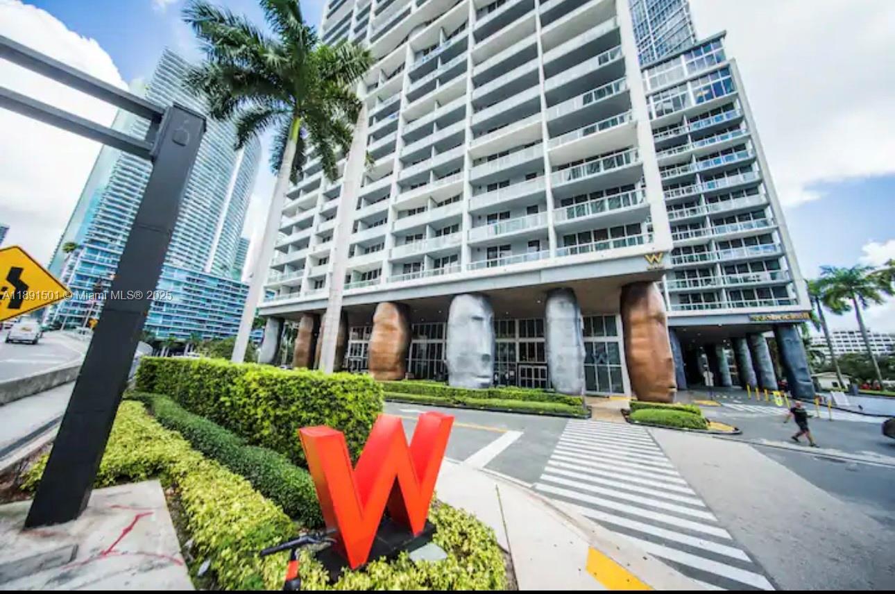 The exterior of a high-rise building features large, face-shaped columns and a prominent red W sign — 495 Brickell Ave # 3706, Miami FL 33131, MIAMI, FL