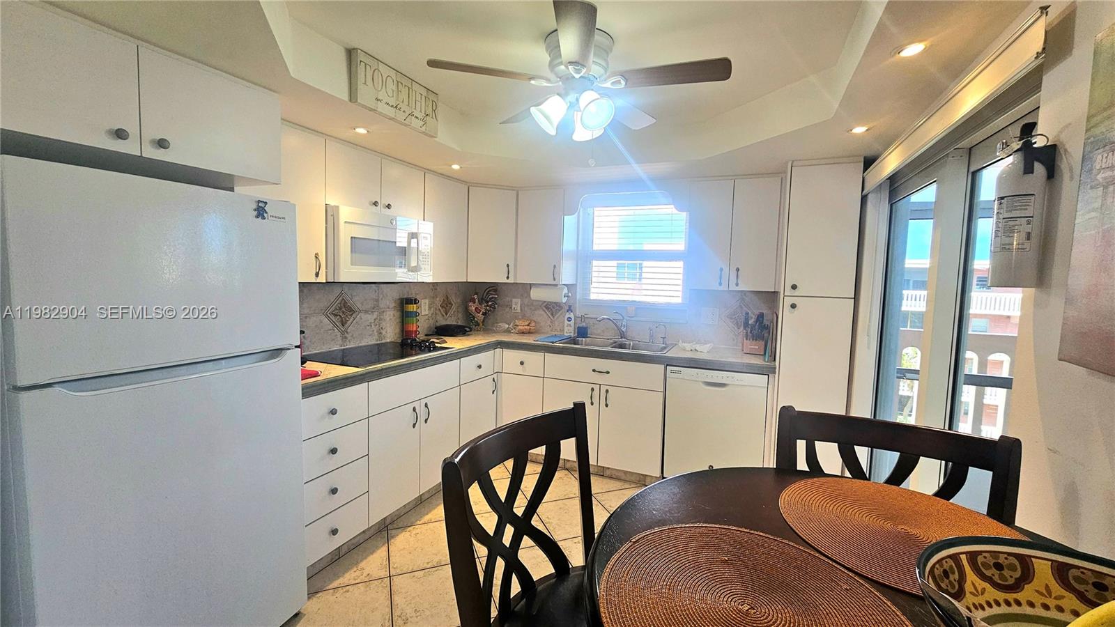 A kitchen features white cabinets, a white refrigerator, a ceiling fan, and a dining table — 180 NE 12th Ave # 10E, Hallandale Beach FL 33009, HALLANDALE BEACH, FL