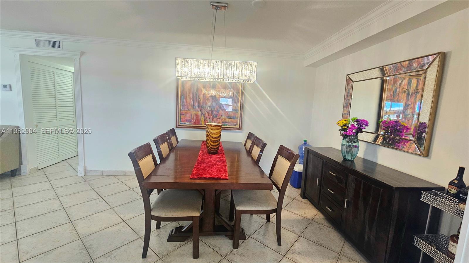A dining room features a wooden table with six chairs, a sideboard, and wall art — 180 NE 12th Ave # 10E, Hallandale Beach FL 33009, HALLANDALE BEACH, FL