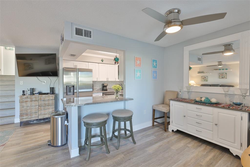 A kitchen with a breakfast bar and stools opens into a living area with cabinetry — 14800 WALSINGHAM ROAD UNIT 1203, LARGO, FL