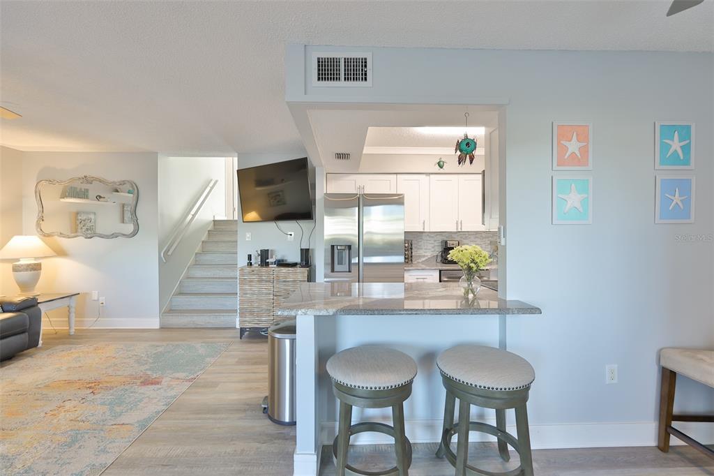 A kitchen with stainless steel appliances and a breakfast bar overlooks a living area — 14800 WALSINGHAM ROAD UNIT 1203, LARGO, FL