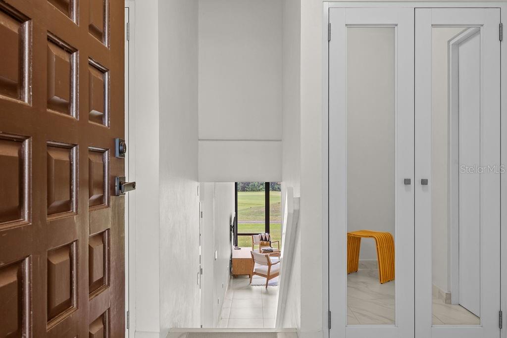 An entryway with a wooden door, mirrored closet doors, and a view down to a room — 310 BEACH VILLAGE DRIVE, HUMACAO, PR