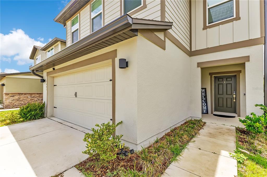 The exterior of a two-story house features a garage, a front entrance, and a concrete walkway — 1687 BEAR MOUNTAIN LANE, MINNEOLA, FL