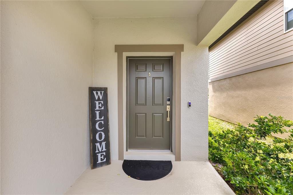 A front entrance features a gray door, a welcome sign, and a black doormat — 1687 BEAR MOUNTAIN LANE, MINNEOLA, FL