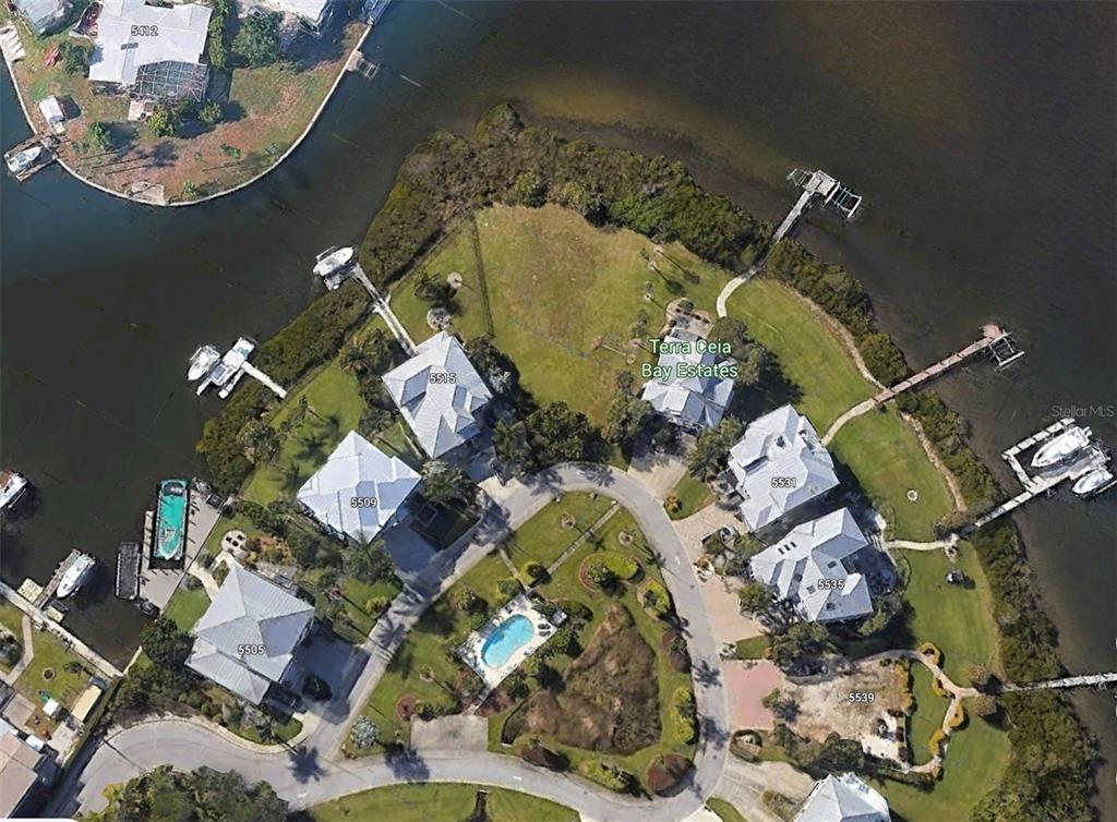 This aerial view shows several waterfront homes with private docks in a coastal neighborhood — 5523 2ND AVENUE CIRCLE W, PALMETTO, FL