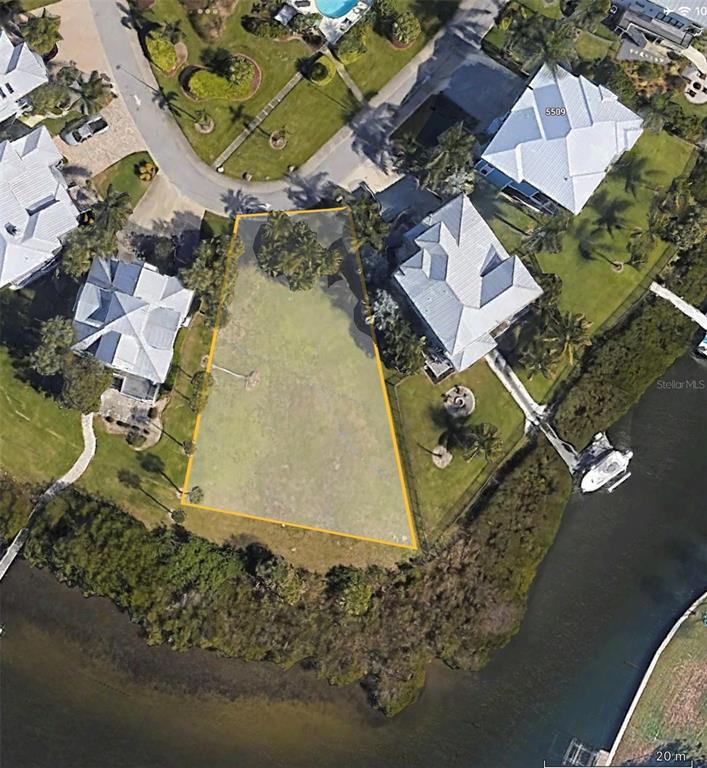 An aerial view shows a vacant waterfront residential lot outlined in yellow between two houses — 5523 2ND AVENUE CIRCLE W, PALMETTO, FL