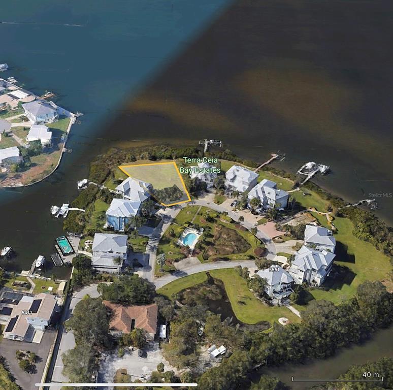 An aerial view shows a vacant waterfront lot outlined in yellow within a residential community — 5523 2ND AVENUE CIRCLE W, PALMETTO, FL