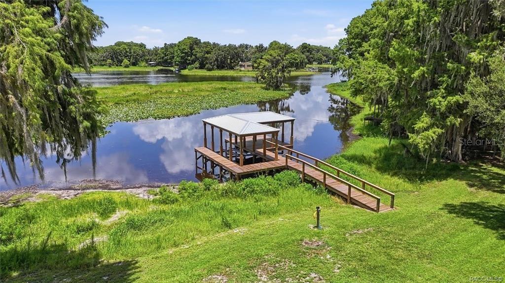 An elevated view of a wooden boat dock extending into a lake with grassy banks — 1425 S HOMESTEAD POINT, INVERNESS, FL