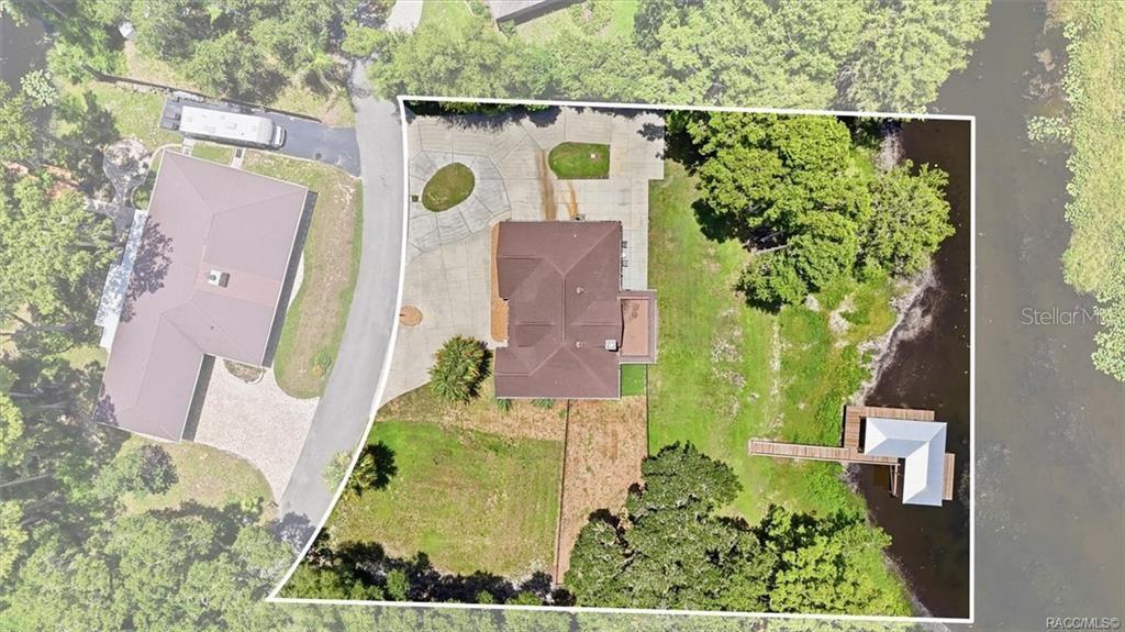 This aerial view shows a house with a large driveway, yard, and private boat dock — 1425 S HOMESTEAD POINT, INVERNESS, FL