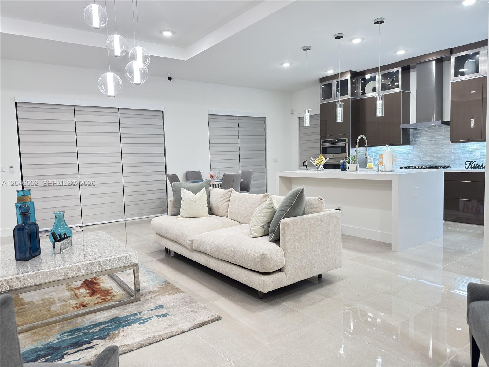 A modern open-concept living room and kitchen feature neutral furniture, tile flooring, and pendant lighting — 5444 SW Saint Armands Way, Westlake FL 33470, WESTLAKE, FL