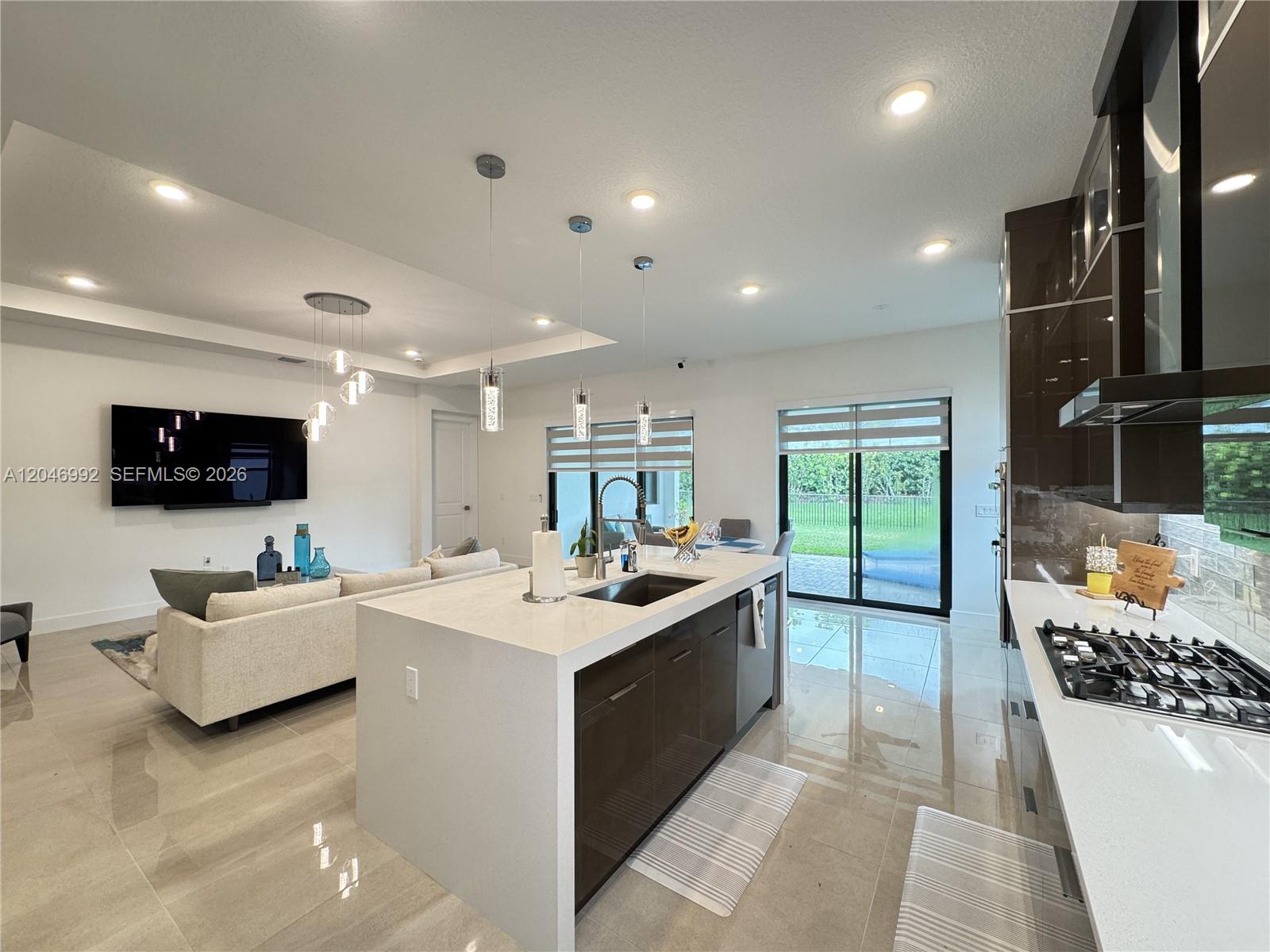 A modern open-concept kitchen features a large quartz island, dark cabinetry, and tile flooring — 5444 SW Saint Armands Way, Westlake FL 33470, WESTLAKE, FL