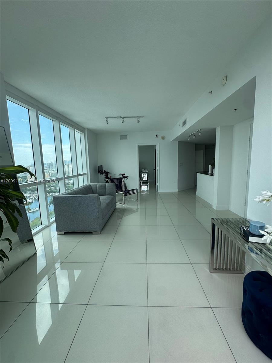 A bright living room features white tile floors, floor-to-ceiling windows, and a gray sofa — 1871 NW S River Dr # 2005, Miami FL 33125, MIAMI, FL