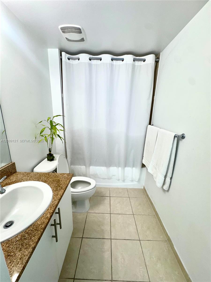 A bathroom features a vanity with a granite countertop, a toilet, and a shower curtain — 1871 NW S River Dr # 2005, Miami FL 33125, MIAMI, FL