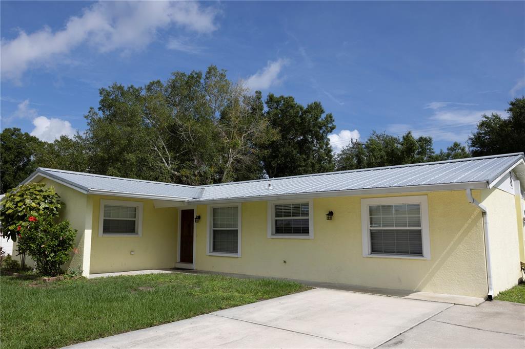 A single-story yellow house with a metal roof and a concrete driveway — 5333 DUNCANWOOD DRIVE, SARASOTA, FL