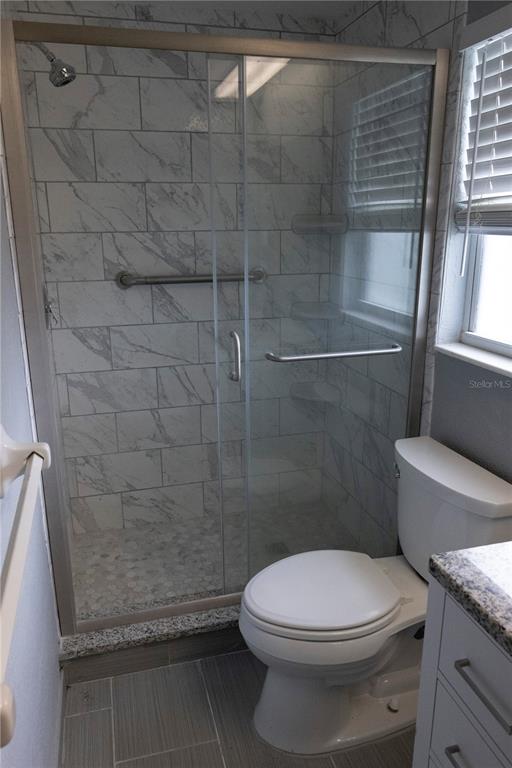 A bathroom features a glass-enclosed shower with marble-look tile, a toilet, and a vanity — 5333 DUNCANWOOD DRIVE, SARASOTA, FL