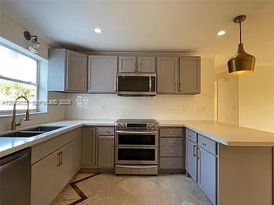 A kitchen features gray cabinets, stainless steel appliances, a white tile backsplash, and a pendant light — 1107 NE 8th St, Hallandale Beach FL 33009, HALLANDALE BEACH, FL