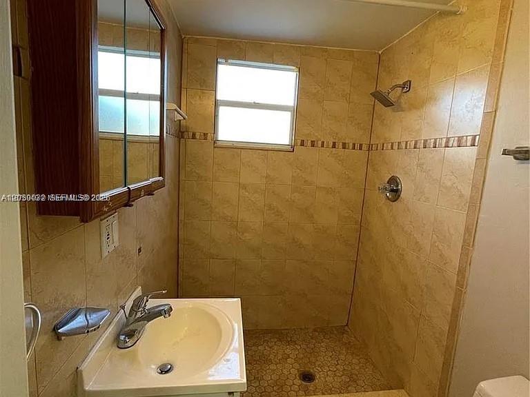 A bathroom features a pedestal sink, a medicine cabinet, and a tiled walk-in shower — 1107 NE 8th St, Hallandale Beach FL 33009, HALLANDALE BEACH, FL