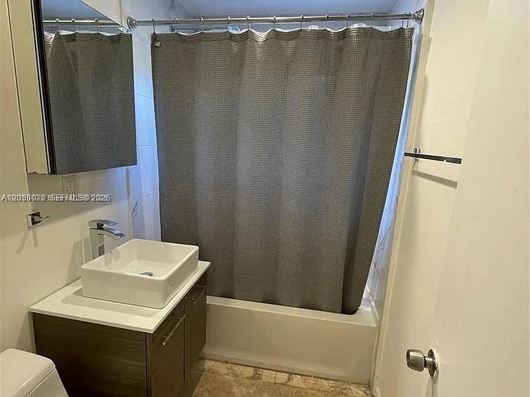 A bathroom features a vessel sink vanity, a mirror cabinet, and a gray shower curtain — 1107 NE 8th St, Hallandale Beach FL 33009, HALLANDALE BEACH, FL